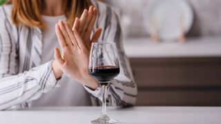 Frau verschränkt die Hände gegenüber einem Weinglas