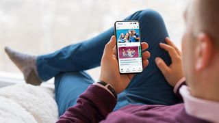 Mann auf dem Sofa schaut auf ein Smartphone-Display