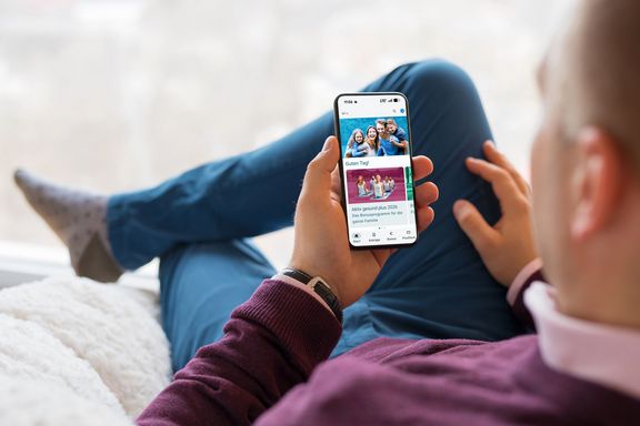 IKK Kunden-App Mann auf dem Sofa schaut auf ein Smartphone-Display