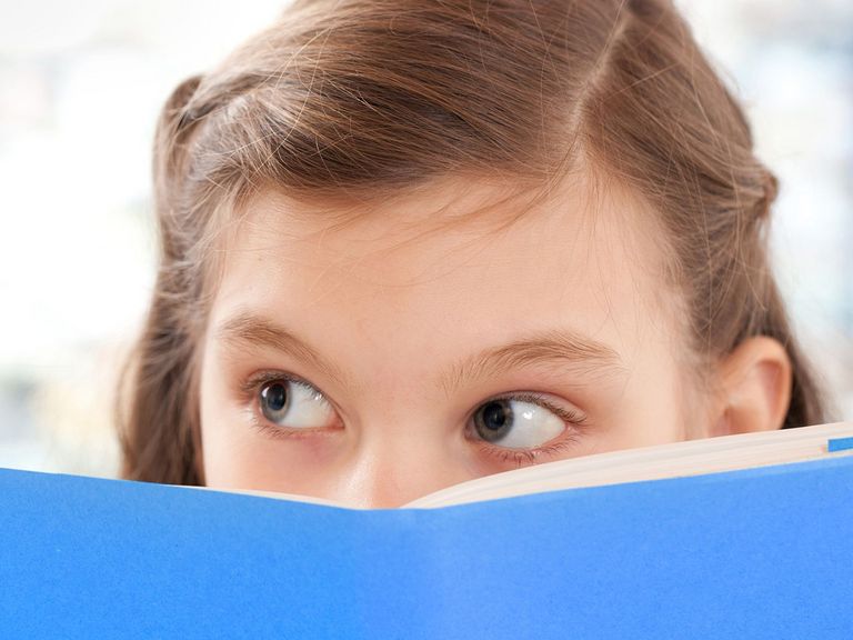Mädchen schaut über einen Schulheftrand hinweg