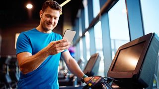 Sportler im Fitnessstudio schaut auf sein Smartphone