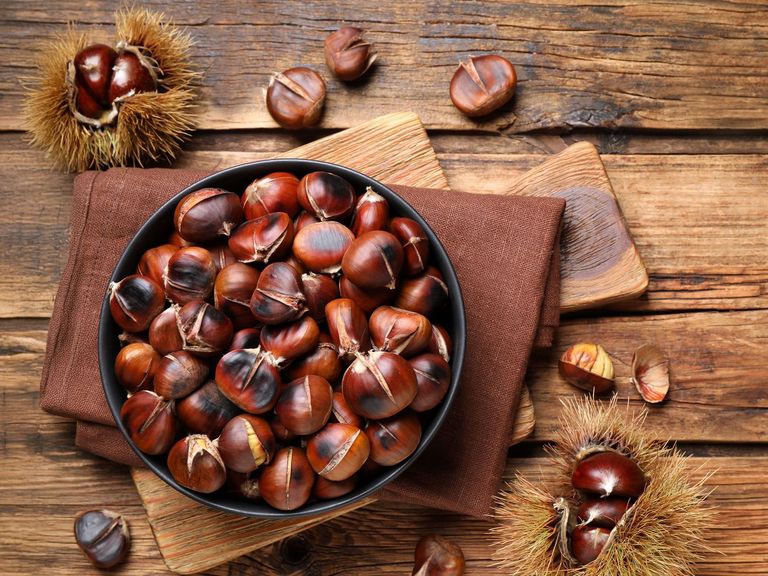 Holztisch mit einer Pfannen voller Esskastanien