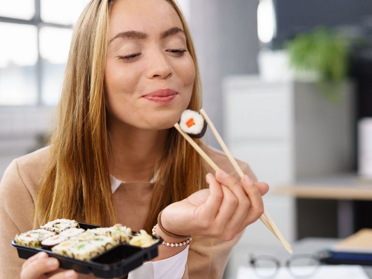 Frau genießt Sushi mit Essstäbchen