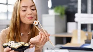 Frau genießt Sushi mit Essstäbchen