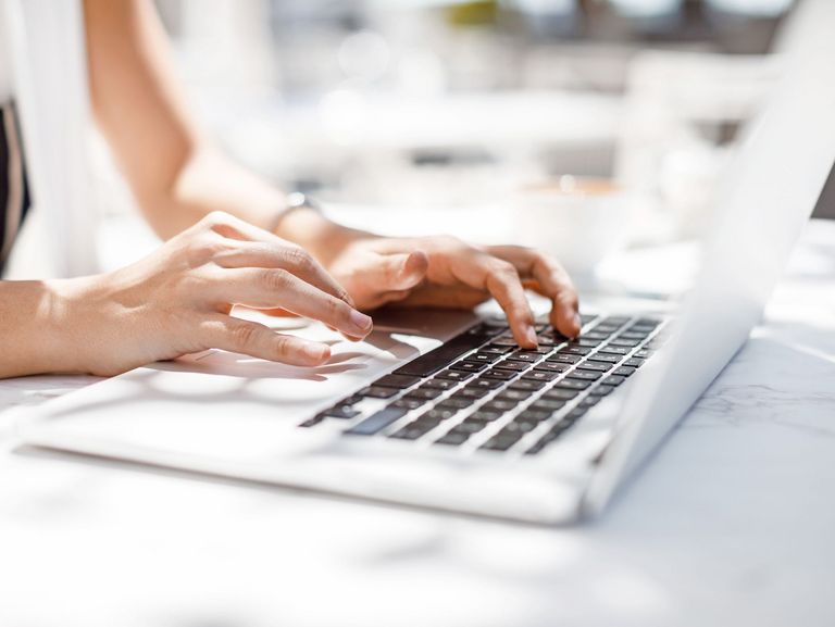 Frauenhände, die auf einer Laptop-Tastatur einen Text tippen