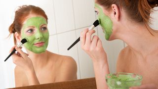 Frau trägt eine grüne Gesichtsmaske auf