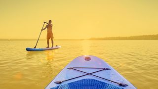 Wassersport Standup-Paddler im Sonnuntergang auf dem See