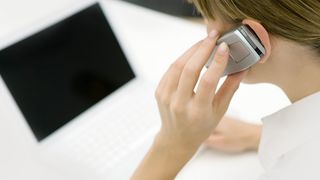 Frau telefoniert am Handy vor Computer
