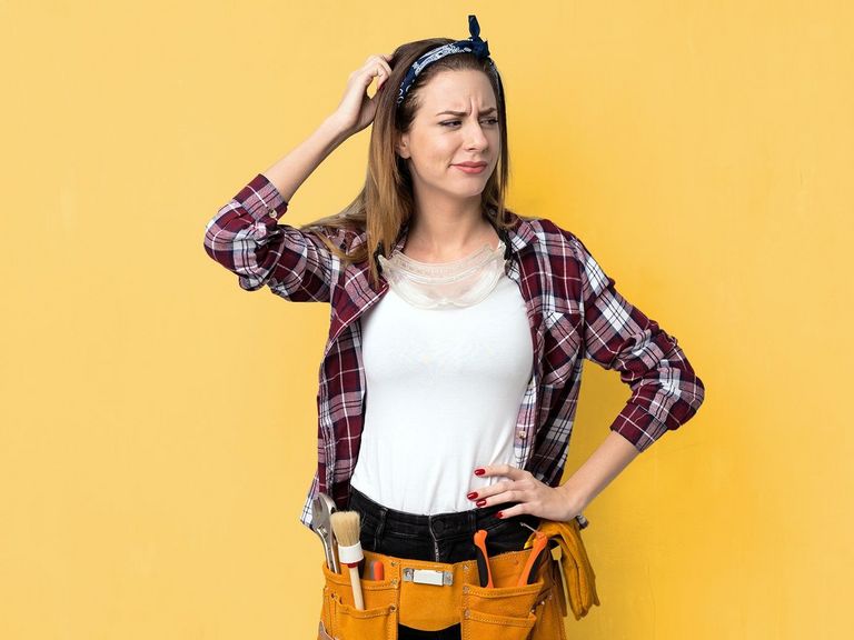 Auszubildende in Arbeitskleidung kratzt sich verlegen am Kopf