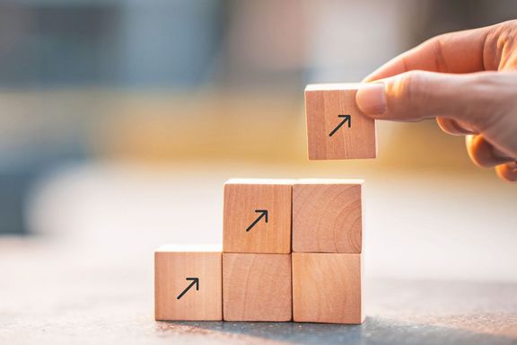 Würfel mit aufgedruckten Nach-oben-Pfeilen werden als Stufen übereinander gestapelt