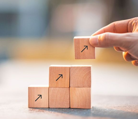 Würfel mit aufgedruckten Nach-oben-Pfeilen werden als Stufen übereinander gestapelt