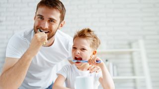 Vater und Sohn putzen sich mit Spaß dabei die Zähne