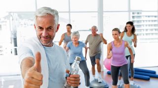 Mann zeigt einen Daumen hoch und im Hintergrund eine Sportlergruppe