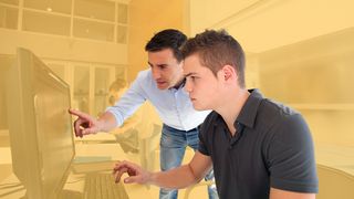 Schülerpraktikum Junger Mann lässt sich am PC-Bildschirm etwas erklären