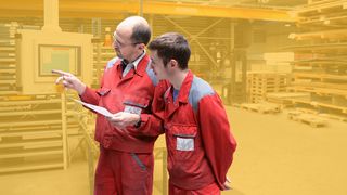 Der Chef erklärt dem Lehrling die Bedienung einer Maschine