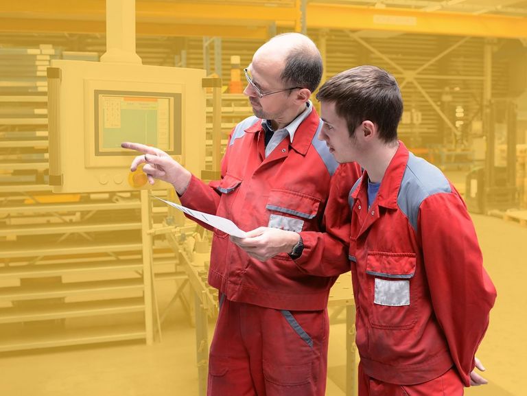 Der Chef erklärt dem Lehrling die Bedienung einer Maschine