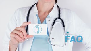 Ärztin hält eine kleine Tafel mit einem aufgedruckten Telefonsymbol in der Hand