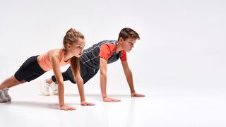 Ein Mädchen und ein Junge in Sportkleidung in Liegestützposition