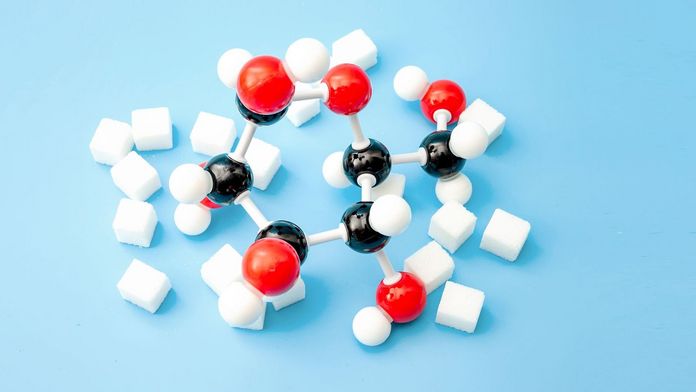 Zucker und chemische Kohlenhydratmodelle auf blauem Hintergrund