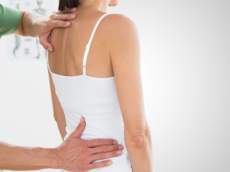 Physiotherapeut untersucht eine junge Frau