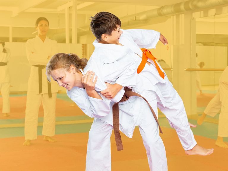 Trainerin der Selbstverteidigung mit ihren Schülern auf der Matte