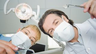 Zahnarzt und Zahnarzthelferin schauen in die Kamera