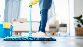 Frau nutzt Wischmopp im Wohnzimmer