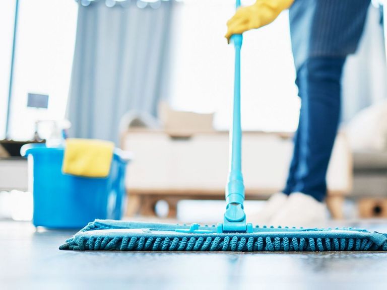 Frau nutzt Wischmopp im Wohnzimmer