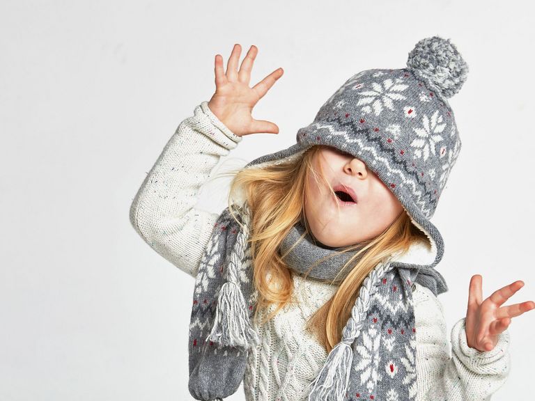 Kind mit dicker Wollmütze macht Faxen