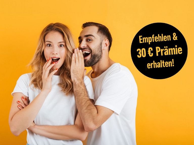 Mann flüstert einer erstaunt schauenden Frau etwas ins Ohr