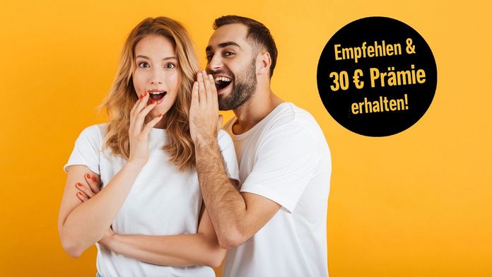 Mann flüstert einer erstaunt schauenden Frau etwas ins Ohr