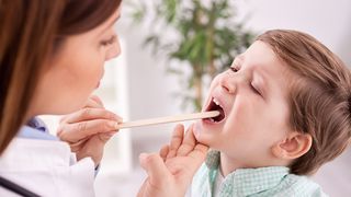 Ärztin schaut die Zunge eines kranken Jungen an