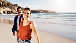 Sommerurlaub Pärchen geht lachend am Strand spazieren