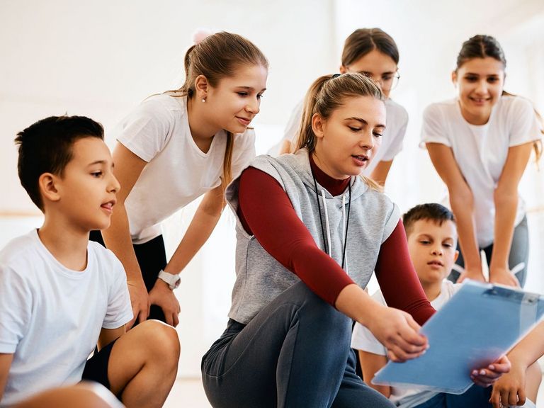 Schüler hören der Sportlehrerin aufmerksam zu