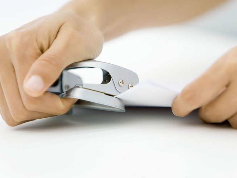 Person benutzt einen Locher für Dokumente