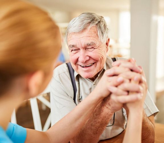 Pflegebedürftiger Rentner freut sich sehr über ein Gespräch mit der Pflegerin