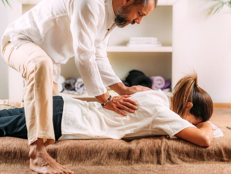 Frau auf einer Bodenmatte bei einer Shiatsu-Massage