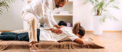 Frau auf einer Bodenmatte bei einer Shiatsu-Massage