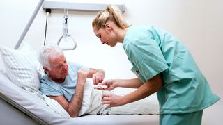 Tages- und Nachtpflege Krankenschwester versorgt einen Pflegebedürftigen mit seinen Medikamenten