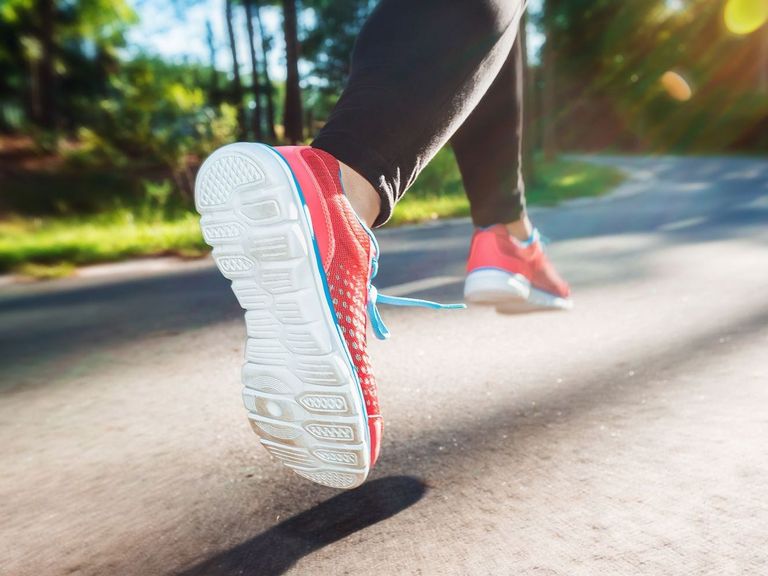 Füße einer aktiven Joggerin auf einer Landstraße