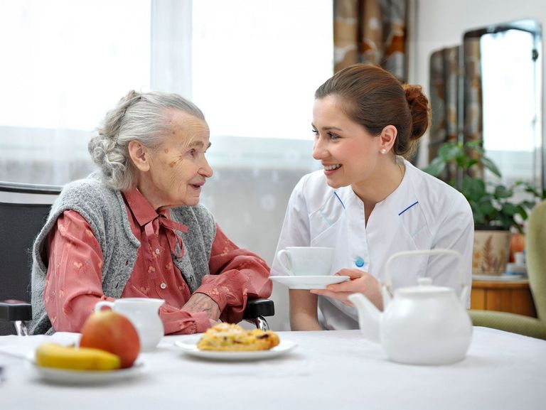 Pflegende betreut eine Rentnerin bei einer Mahlzeit