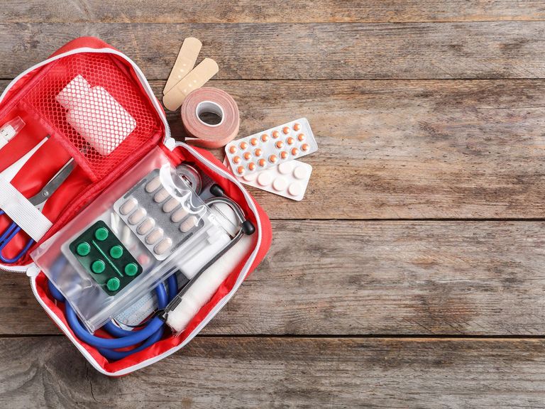 Geöffnete Hausapothekentasche auf einem Holztisch