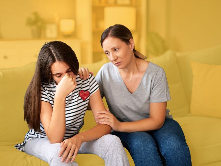 Mutter tröstet im Wohnzimmer ihre gestresste Tochter