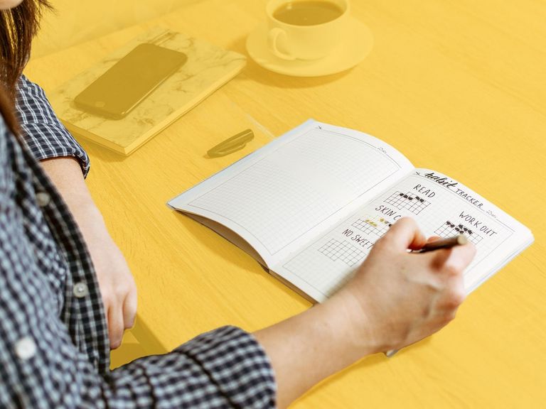 Jugendliche schreibt etwas in ein Bullet Journal