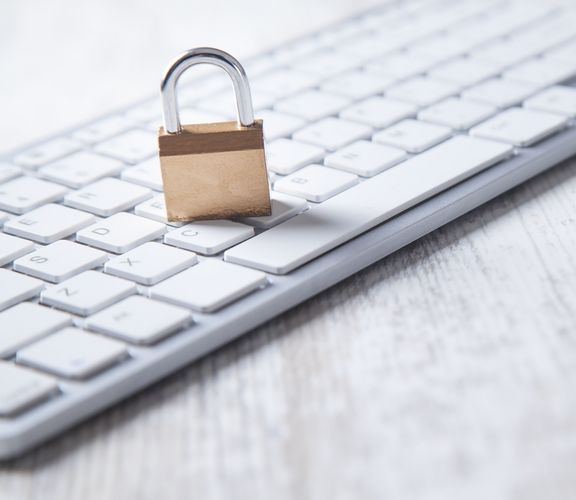 Graue Laptoptastatur mit einem darauf liegendem kleinen symbolischen Schloss 