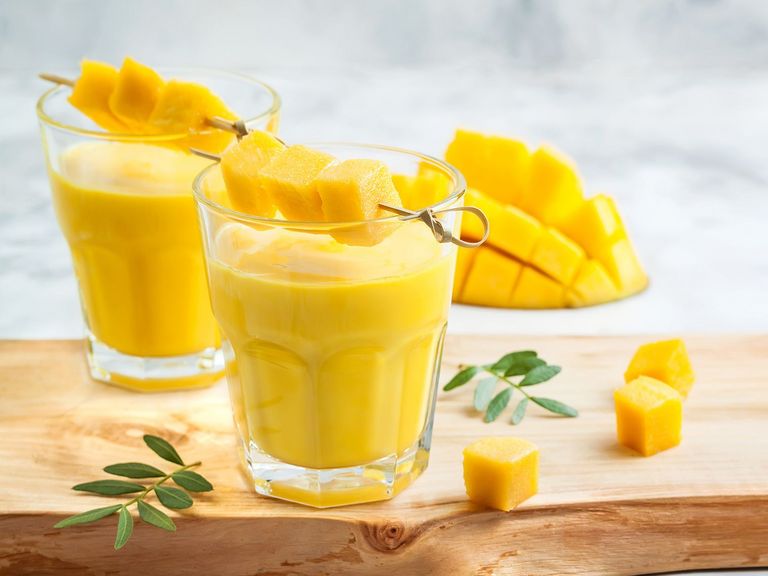 Zwei Gläser mit Mango-Lassi und Mangostücken als Deko
