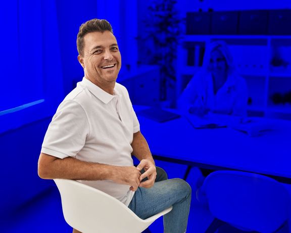 Mann beim Arztgespräch schaut über die Schulter zurück