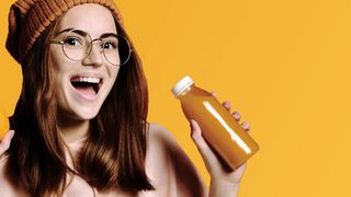 Junge Frau mit einer Orange und einem Apfel in der Hand