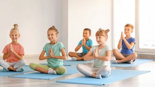 Mind-Factory | Grundschule Schüler sitzen auf einer Matte im Schneidersitz und entspannen