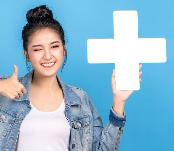 Junge Frau vor cyan-blauem Hintergrund hält ein großes "Plus" in der Hand und zeigt "Daumen hoch"